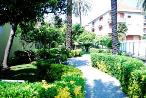 a walkway through a garden with palm trees and bushes at affascinante bilocale con piscina in Bordighera