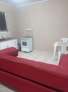sala de estar con sofá rojo y cocina en Residencial Barbosa - Apto 302, en Macaé