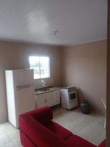 a kitchen with a refrigerator and a red couch at Residencial Barbosa - Apto 302 in Macaé