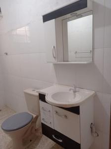uma casa de banho com um WC, um lavatório e um espelho. em Residencial Barbosa - Apto 302 em Macaé