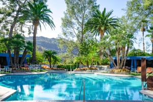 a pool with palm trees and mountains in the background at Hilton Los Angeles-Universal City in Los Angeles