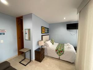 1 dormitorio con 1 cama blanca y TV en Brisas de Guatape en Guatapé