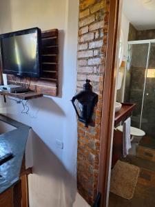 a bathroom with a tv on a brick wall at Chácara ladeira de Pedra in Salesópolis