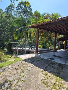 a pavilion with a picnic table and a bench at Chácara ladeira de Pedra in Salesópolis