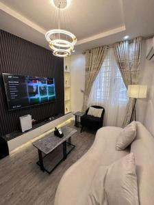 a living room with a couch and a flat screen tv at Cheapest luxury 1 bedroom apartment in Katampe Ext in Gwarinpa