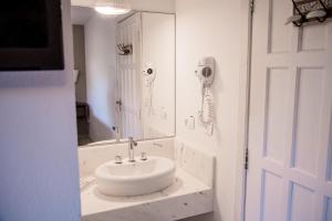 a white bathroom with a sink and a mirror at alua pousada ventos de camburi in Camburi