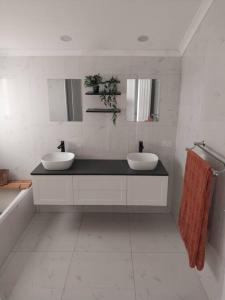 卡倫德拉的住宿－9 Room Family & Pet Friendly Home，浴室设有两个盥洗盆和一个带镜子的黑色柜台。