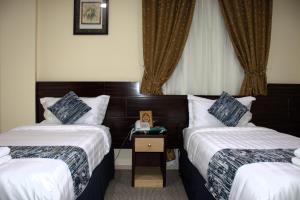 a hotel room with two beds and a telephone at فندق لؤلؤة العنود مكة Loulouat Al Anood Hotel Mecca in Makkah