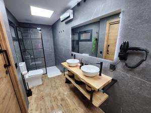 une salle de bain avec deux lavabos sur une table en bois dans l'établissement Bailén 3, à Cáceres 28 autres photos