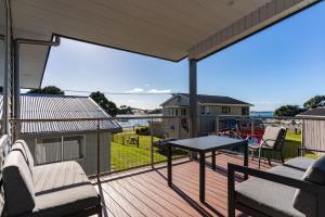 een terras met een tafel en stoelen bij The Daydreamer - Mangawhai Heads Holiday Home in Mangawhai