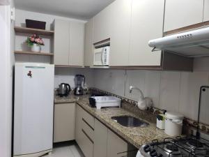 een keuken met witte kasten en een witte koelkast bij Apartamento Aconchegante para duas pessoas in Gravataí