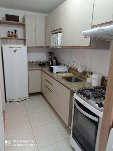 een keuken met een witte koelkast en een fornuis top oven bij Apartamento Aconchegante para duas pessoas in Gravataí