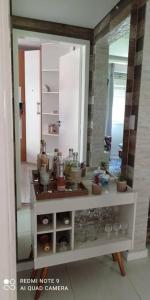 een kamer met een spiegel en een plank met glazen bij Apartamento Aconchegante para duas pessoas in Gravataí