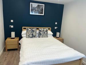een slaapkamer met een bed met een blauwe muur bij Priory Tearooms Burford with Rooms in Burford