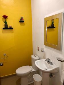 a yellow bathroom with a toilet and a sink at Mayan Plaza Hermosa Habitación a 3 cuadras del Parque in Copán Ruinas