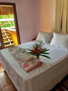 a white bed with a vase of flowers on it at Blue Ocean Flats in Itacaré