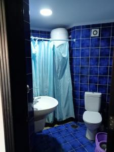 a blue tiled bathroom with a toilet and a sink at Porto Matroh For Family in Marsa Matruh