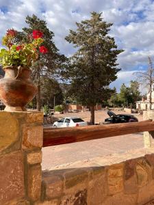a vase with red flowers on a stone wall at Hotel La Herencia in Tilcara