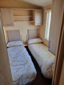 two beds in a small room in a caravan at Palm Grove 110 in Chapel Saint Leonards