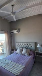 1 dormitorio con cama morada y techo en Cómodo dúplex frente al mar, en Monte Hermoso