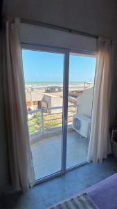 una puerta corredera de cristal con vistas a la playa en Cómodo dúplex frente al mar, en Monte Hermoso