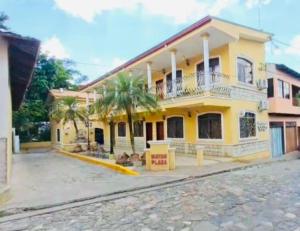 コパン・ルイナスにあるMayan Plaza Hermosa Habitación a 3 cuadras del Parqueのヤシの木が目の前に広がる黄色い家