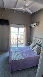 Un dormitorio con una cama y una ventana grande. en Cómodo dúplex frente al mar, en Monte Hermoso