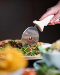 a person cutting a pizza with a pizza cutter at DoubleTree by Hilton Hotel Newcastle International Airport in Newcastle upon Tyne