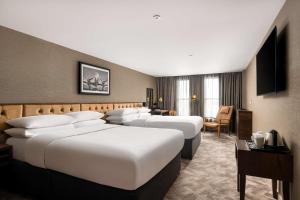 a hotel room with four beds and a television at DoubleTree by Hilton Hotel Newcastle International Airport in Newcastle upon Tyne