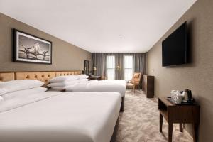 a hotel room with four beds and a television at DoubleTree by Hilton Hotel Newcastle International Airport in Newcastle upon Tyne