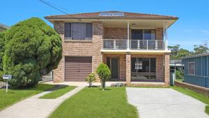 una casa de ladrillo con un árbol delante de ella en Sylvia's at Currarong, en Currarong
