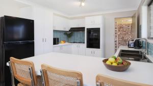 a white kitchen with a bowl of fruit on a counter at Sylvia's at Currarong in Currarong