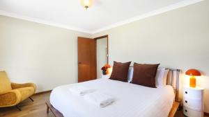 a bedroom with a white bed and a chair at Sylvia's at Currarong in Currarong