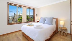 a bedroom with a large white bed and a window at Sylvia's at Currarong in Currarong +20 photos