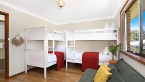 1 dormitorio con 2 literas y sofá en Sylvia's at Currarong, en Currarong