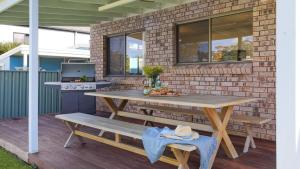 Una mesa de picnic y un banco en un patio. en Sylvia's at Currarong, en Currarong