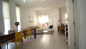 a living room with a table and yellow chairs at Quarto Privativo em Casa Linda in Sorocaba