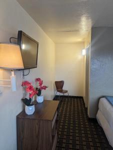 a room with a bed and a desk with flowers on it at Southern Comfort Hotel in Tulsa