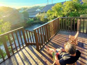 菊川市的住宿－yadoru-i-to-ko-to - Vacation STAY 14261，坐在阳台上甲板上的男人