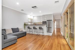 ein Wohnzimmer mit einem Sofa und einer Küche in der Unterkunft Brompton Bliss - A Relaxed Northern Adelaide Retreat in Bowden