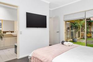 a bedroom with a bed with a television on a wall at Brompton Bliss - A Relaxed Northern Adelaide Retreat in Bowden