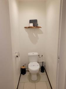 a bathroom with a toilet and a shelf on the wall at Hudace in Saint-Laurent du Maroni