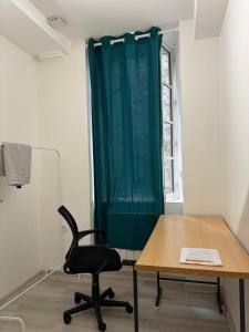 einen Schreibtisch und einen Stuhl in einem Zimmer mit einem grünen Vorhang in der Unterkunft Moonlight in Chambéry