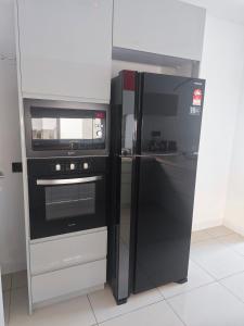eine Küche mit einem schwarzen Kühlschrank und einer Mikrowelle in der Unterkunft M-Residence in Pantai Cenang