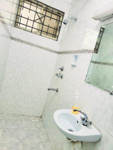a white bathroom with a sink and a mirror at SwanLakeview3br, Wi-Fi, Netflix, Balcony, Sunset. in Kisumu