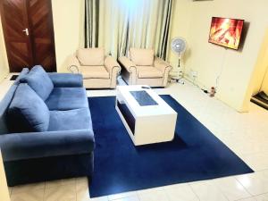 a living room with a blue couch and two chairs at SwanLakeview3br, Wi-Fi, Netflix, Balcony, Sunset. in Kisumu