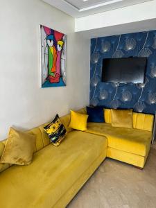 Yanis guest house في الدار البيضاء: أريكة صفراء في غرفة المعيشة مع لوحة