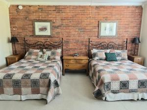 een slaapkamer met 2 bedden en een bakstenen muur bij Eagles Nest Inn in Louisiana