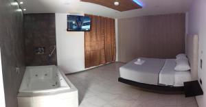 Hostal Zafiro في Sangolquí: غرفة نوم بسرير وحوض استحمام وتلفزيون