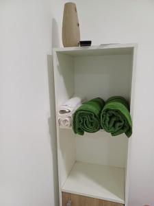- un placard blanc avec des serviettes vertes sur une étagère dans l'établissement Lo de Tomy, à Río Grande